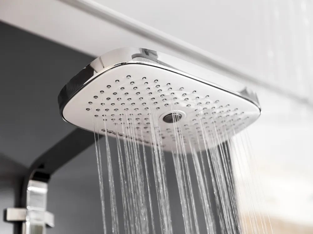 A newly installed rain showerhead running in a modern bathroom