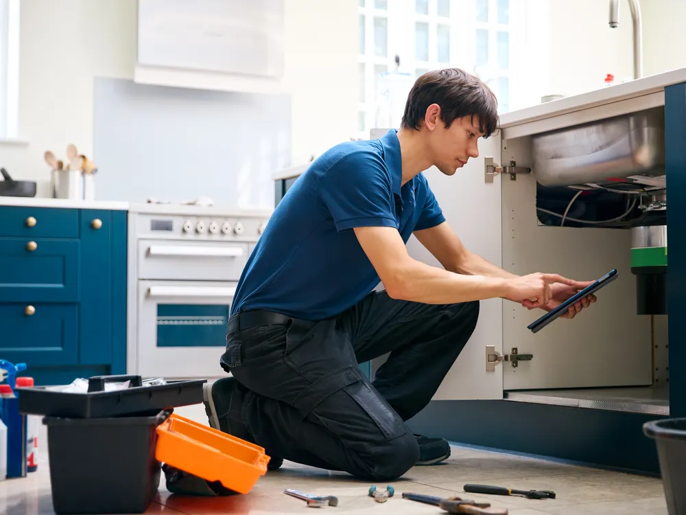Licensed plumber checking his work under a kitchen sink