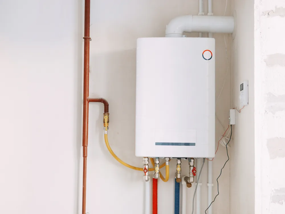 A wall-mounted tankless water heater with its hot, cold, and gas lines connected